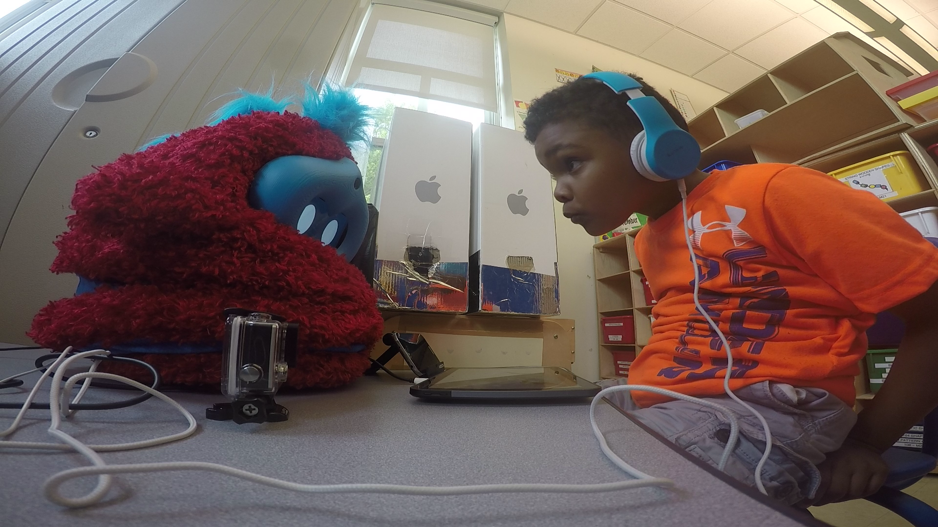 child peers at furry robot across a table
